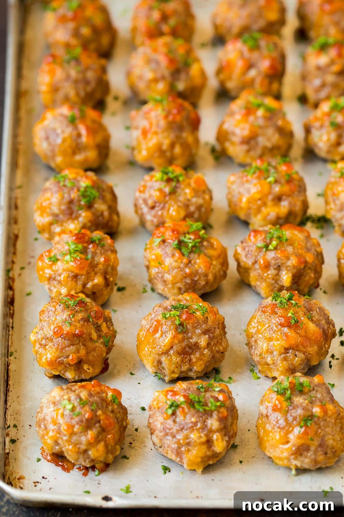 Classic Southern Sausage Balls Recipe with Cheesy Biscuits 6 Cooked sausage balls on a pan, topped with parsley.