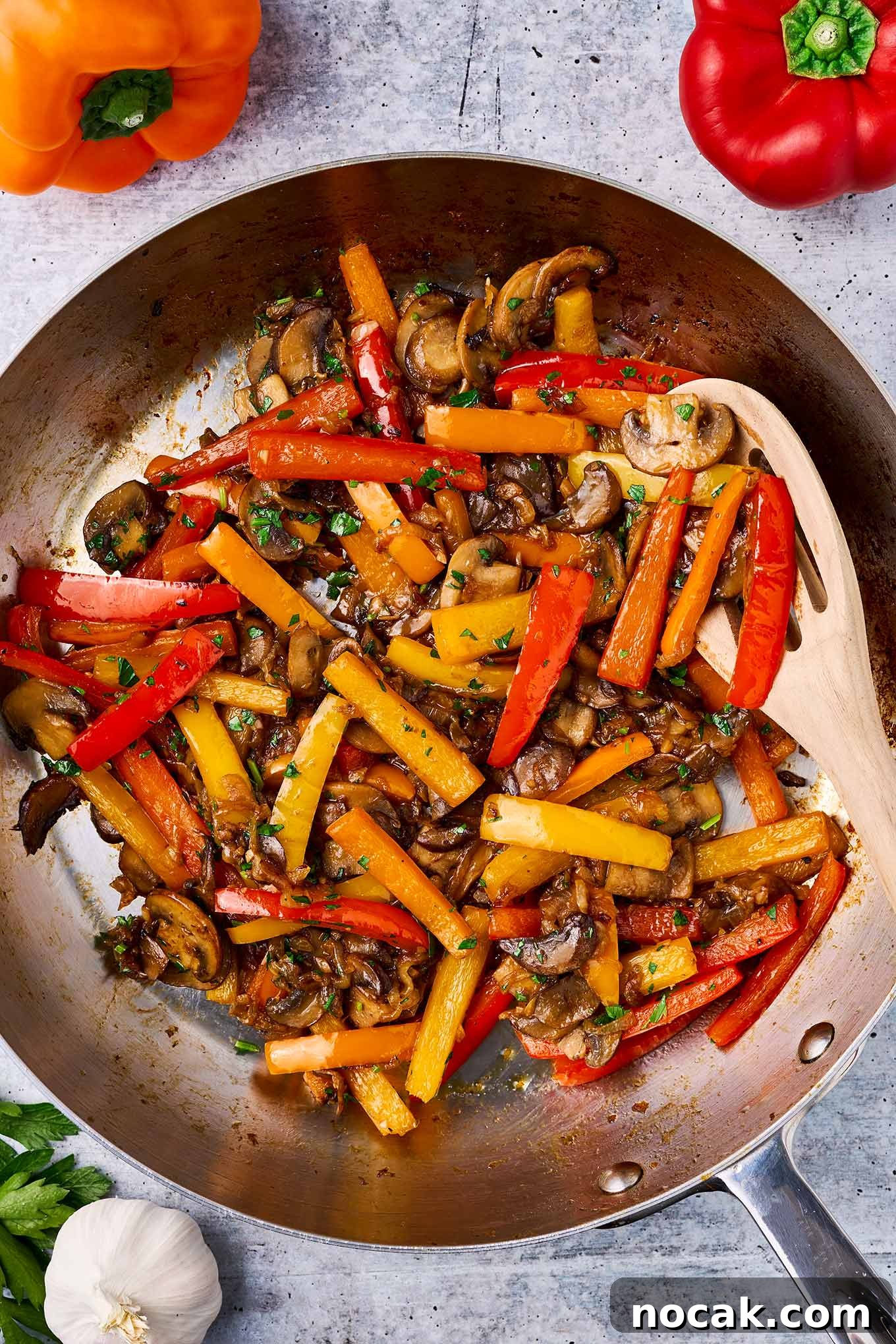 Sautéed Peppers, Mushrooms & Onions Recipe for Flavorful Sides 4 Stirring peppers, mushrooms and onions with a wooden spoon in a frying pan with balsamic vinegar and fresh chopped parsley sprinkled on top.