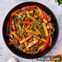 Sautéed Peppers, Mushrooms & Onions Recipe for Flavorful Sides 6 Sautéed peppers, mushrooms and onions with a sprinkle of fresh chopped parsley, served in a black ceramic bowl.
