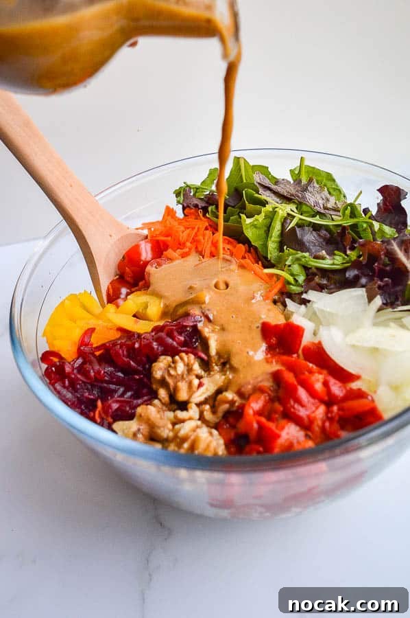 Whole30 Balsamic Mustard Salad Dressing Recipe 3 Pouring a creamy balsamic dressing onto a chopped salad in a glass bowl