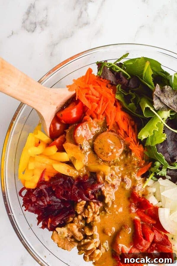 Whole30 Balsamic Mustard Salad Dressing Recipe 4 A bowl of vegetables with a golden dressing poured all over on a white marble background