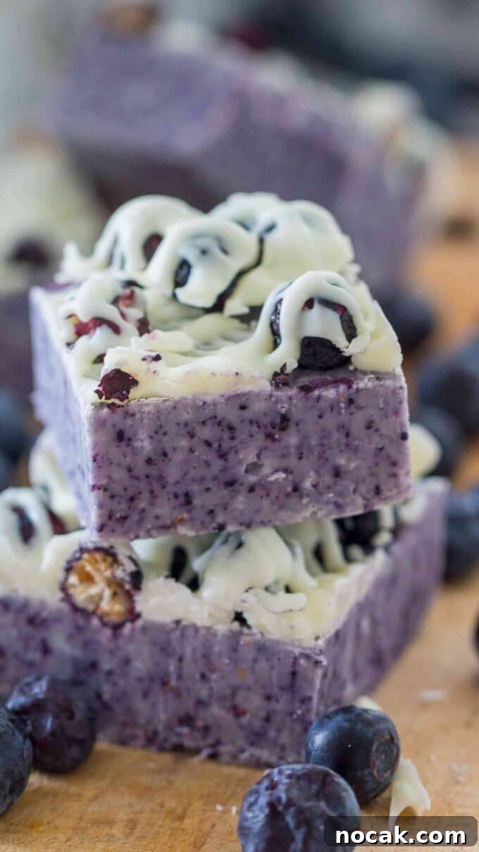 Creamy No-Bake Blueberry Fudge Recipe 13 Blueberry fudge square topped with white chocolate and blueberries.