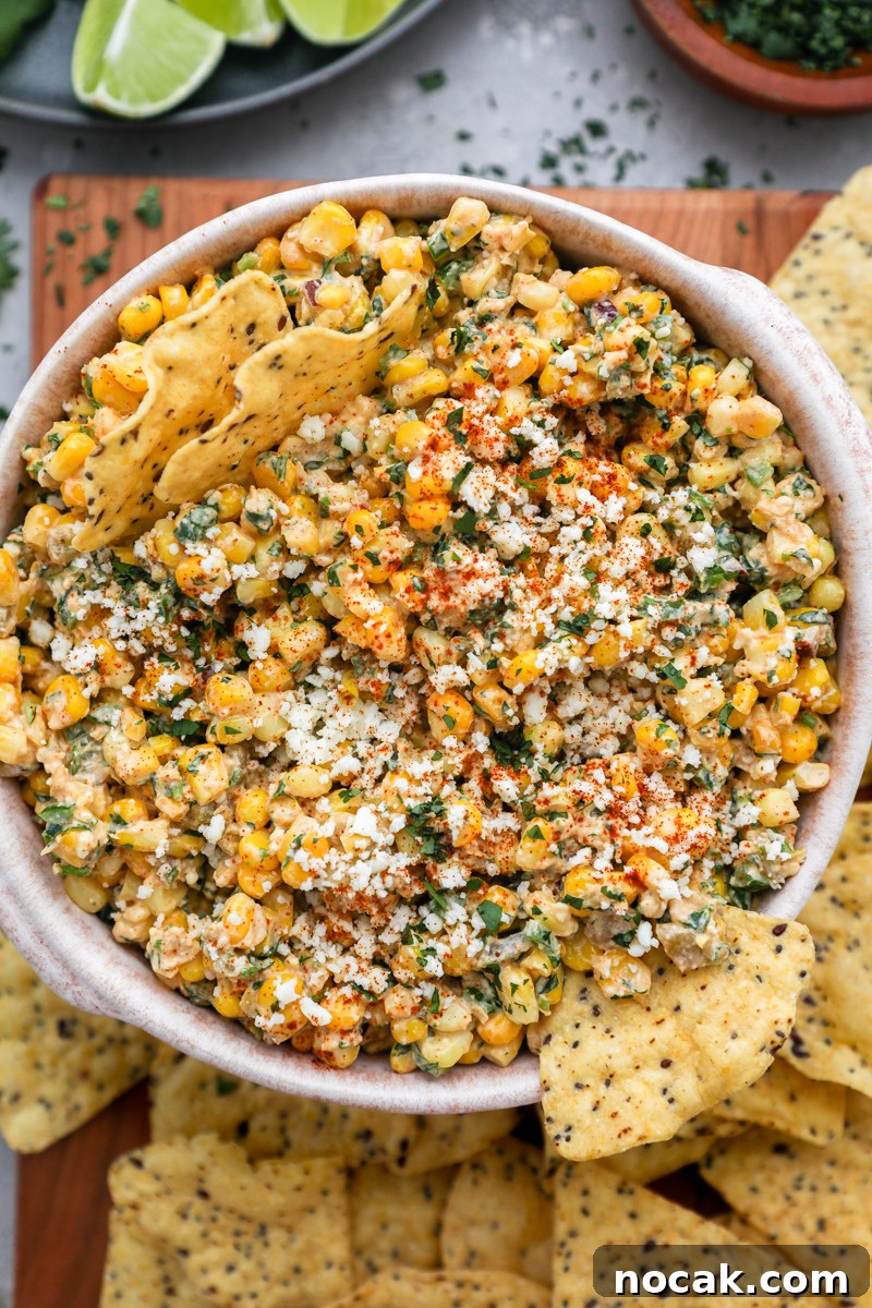 Mexican Street Corn Dip Recipe: Creamy Elote-Inspired Dip 6 A close up photo of MExican street corn dip sprinkled with cotija cheese, chopped cilantro and chili powder on top