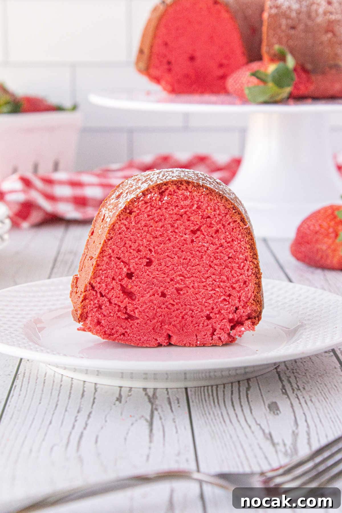 Old-Fashioned Strawberry Pound Cake with Cream Cheese Frosting 7 A slice on strawberry bundt cake on a white plate showing the beautiful red coloring of the cake.