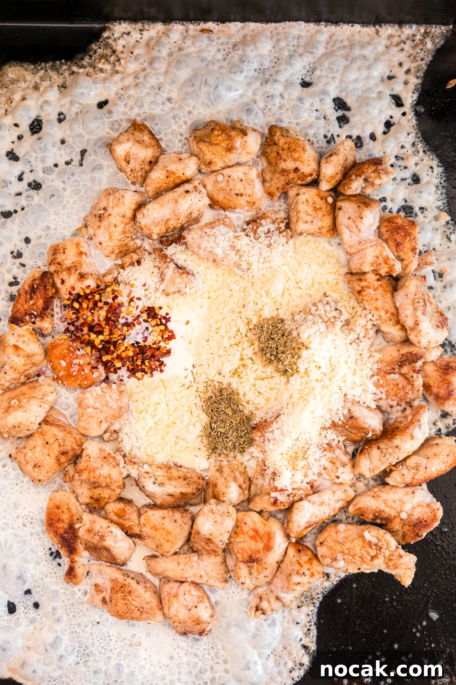 Blackstone Marry Me Chicken Recipe: Skillet Chicken with Creamy Sun-Dried Tomato Sauce 6 Cooked chicken pieces are arranged in a circle on a griddle while cream, grated cheese, red pepper flakes, and dried herbs melt together in the center to form a sauce.