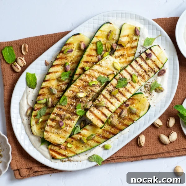 An overhead image of grilled zucchini with tahini sauce on the side.