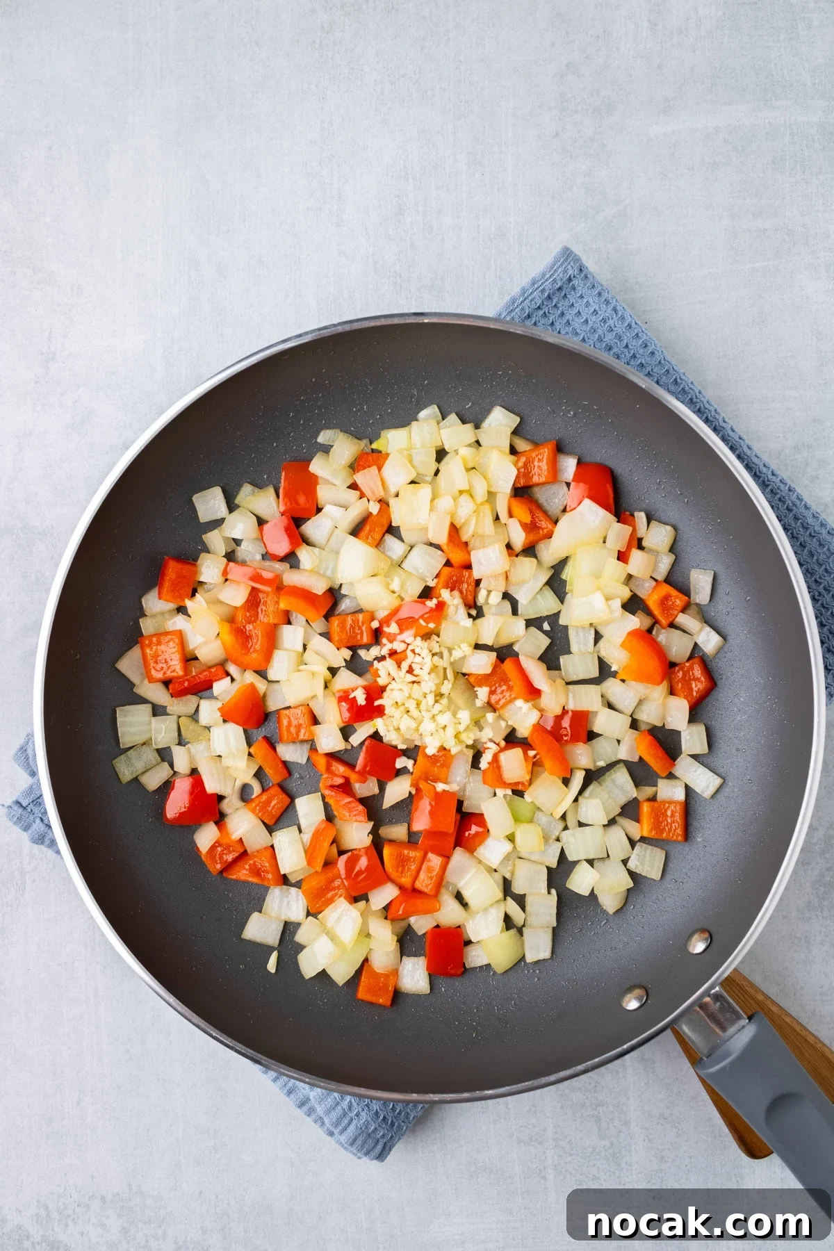 An overhead image of sautéing bell peppers, onions, and garlics to a skillet.