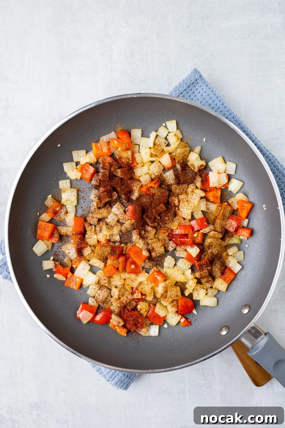 An overhead image of adding spices to the skillet.