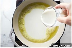Creamy Chicken Alfredo Tortellini Recipe for Quick Weeknight Dinner 9 Hand pours milk into melted butter in a skillet.