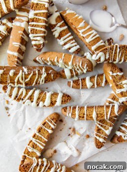 white chocolate drizzled gingerbread biscotti scattered over wrinkled wax paper