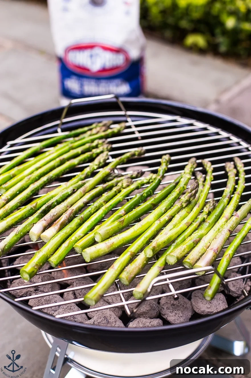 Asparagus grilling on a small round charcoal grill