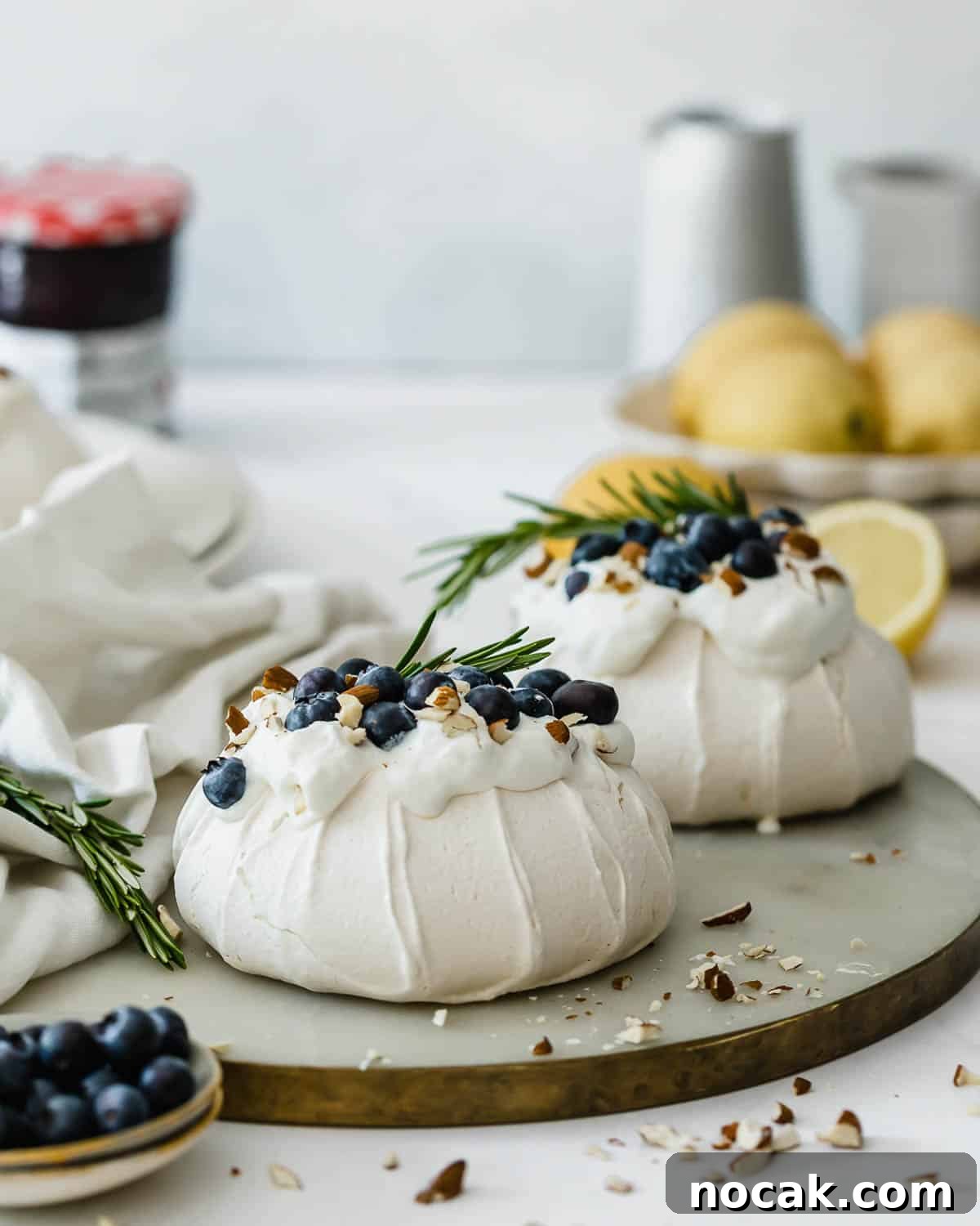 Mini Pavlova Nests Recipe: Crispy Meringue Nests with Berries 2 Two mini pavlova nests topped with whipped cream, fresh blueberries, and almonds.