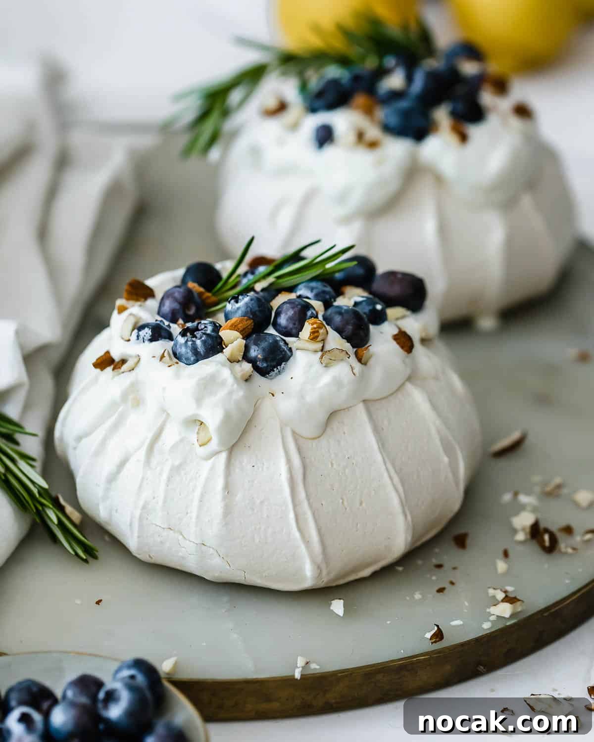 Mini Pavlova Nests Recipe: Crispy Meringue Nests with Berries 3 Two mini pavlova sitting on a marble serving tray.