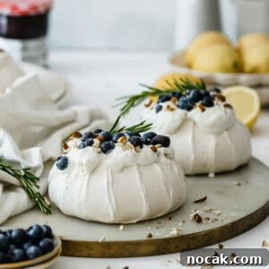 Mini Pavlova Nests Recipe: Crispy Meringue Nests with Berries 6 Two mini pavlova nests sitting on a marble serving tray.