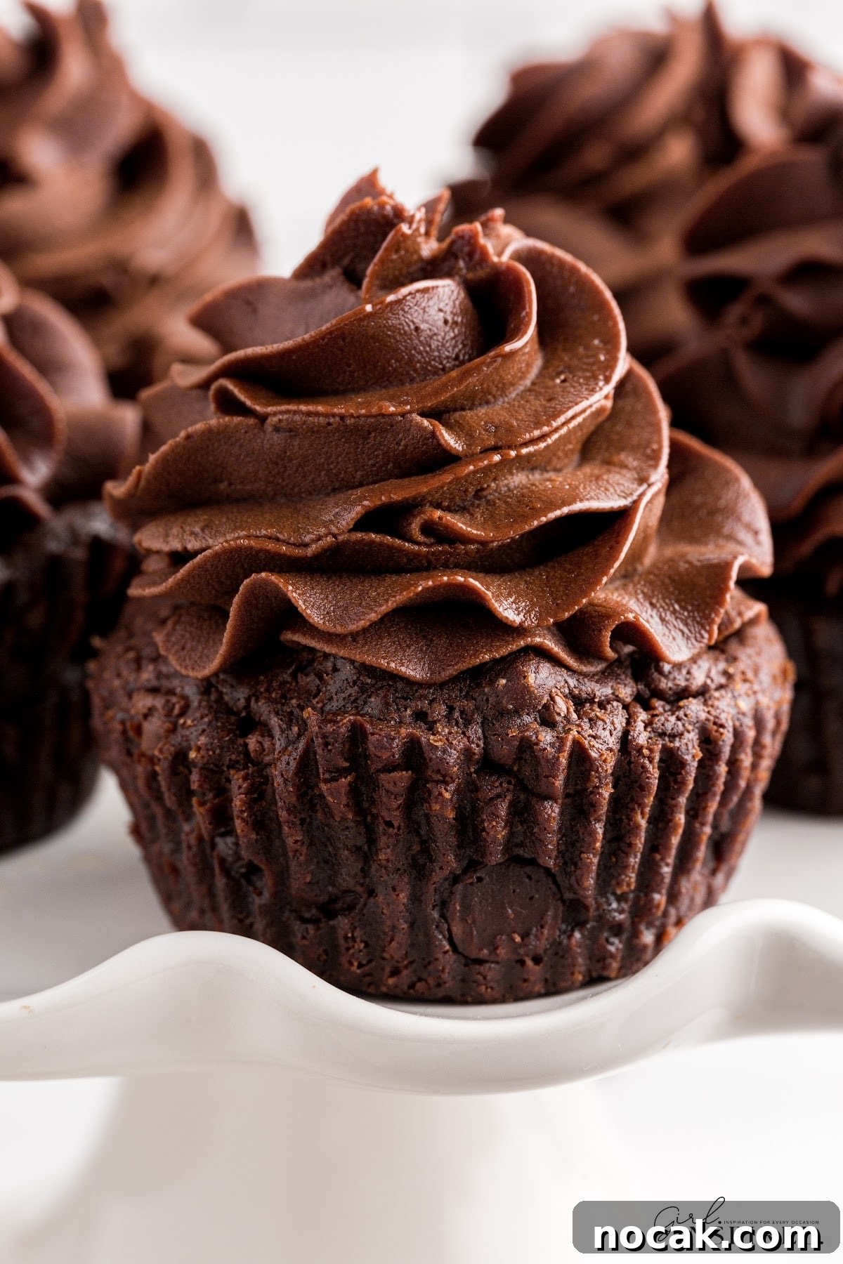 Fudgy Brownie Cupcakes with Gooey Chocolate Centers 15 Close up of a Brownie Cupcake, showing the frosting and other cupcakes in the background.