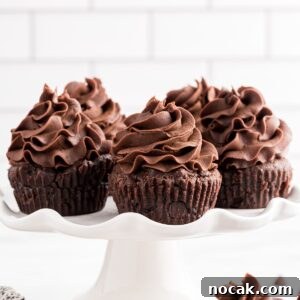 Fudgy Brownie Cupcakes with Gooey Chocolate Centers 20 Brownie Cupcakes on a serving platter, frosted, and one cupcake just under the platter.