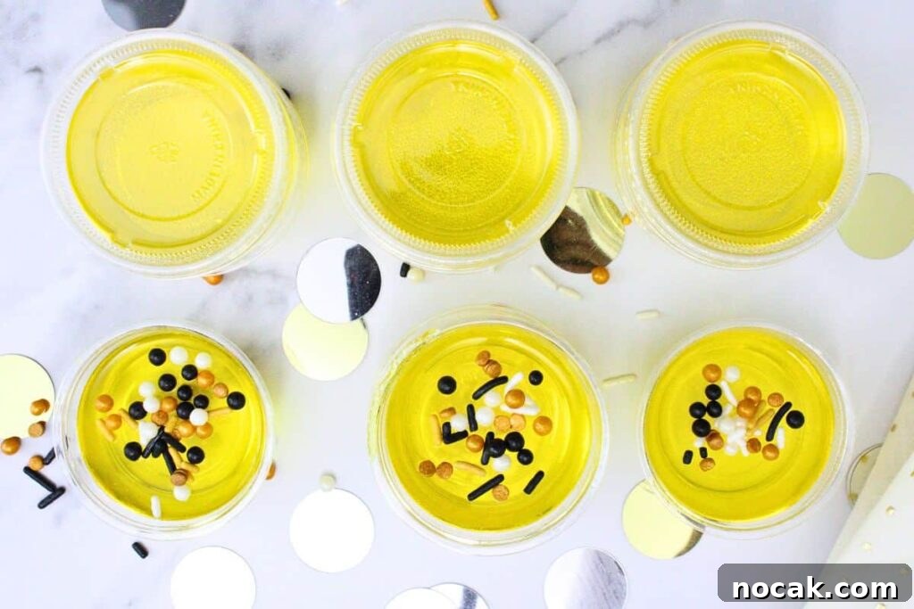 French 75 Jello Shots for a Sparkling New Year’s Party 8 overhead view of golden french 75 jello shots topped with black and gold sprinkles on a white counter