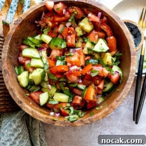 Cucumber and Tomato Salad with Fresh Herbs and Lemon Dressing 6 Wooden bowl with tomatoes and cucumber in it, red pepper flakes on the side.