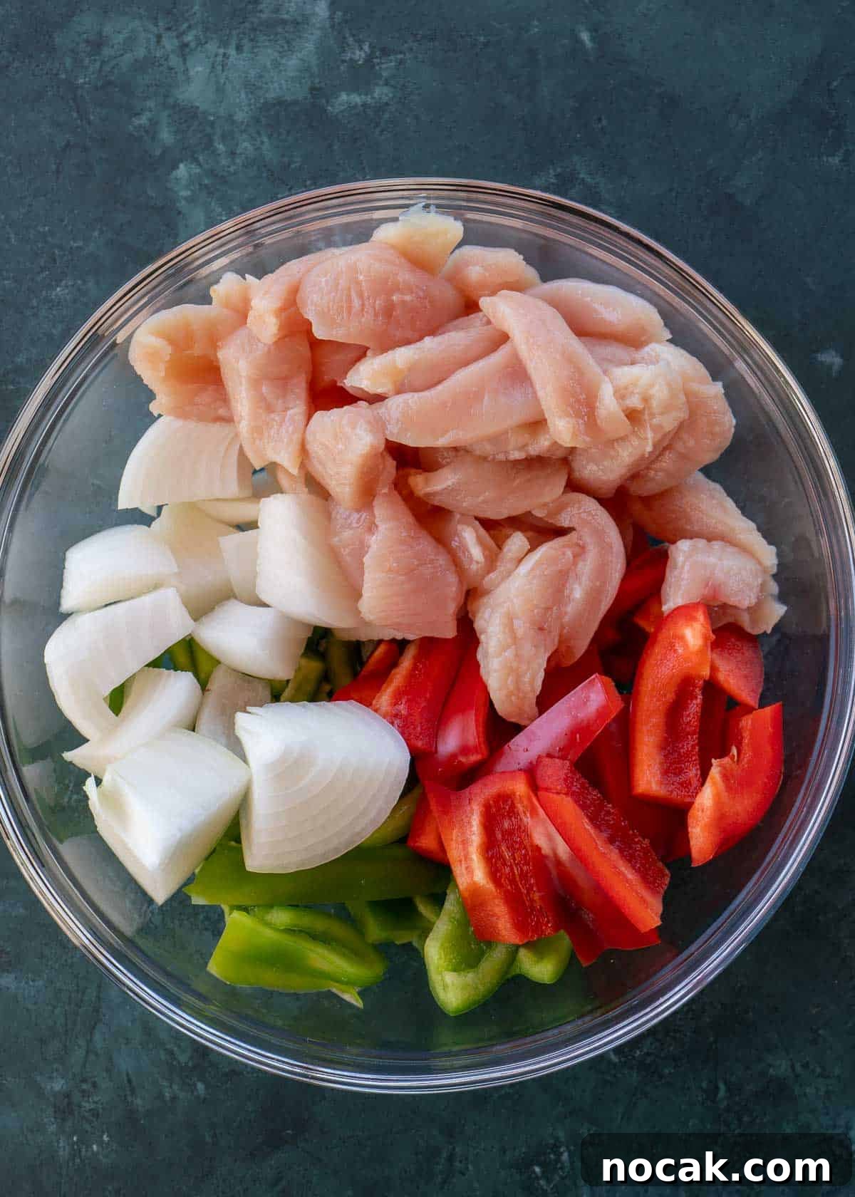 Crispy Air Fryer Chicken Fajitas with Peppers and Onions 5 sliced chicken and vegetables in mixing bowl.