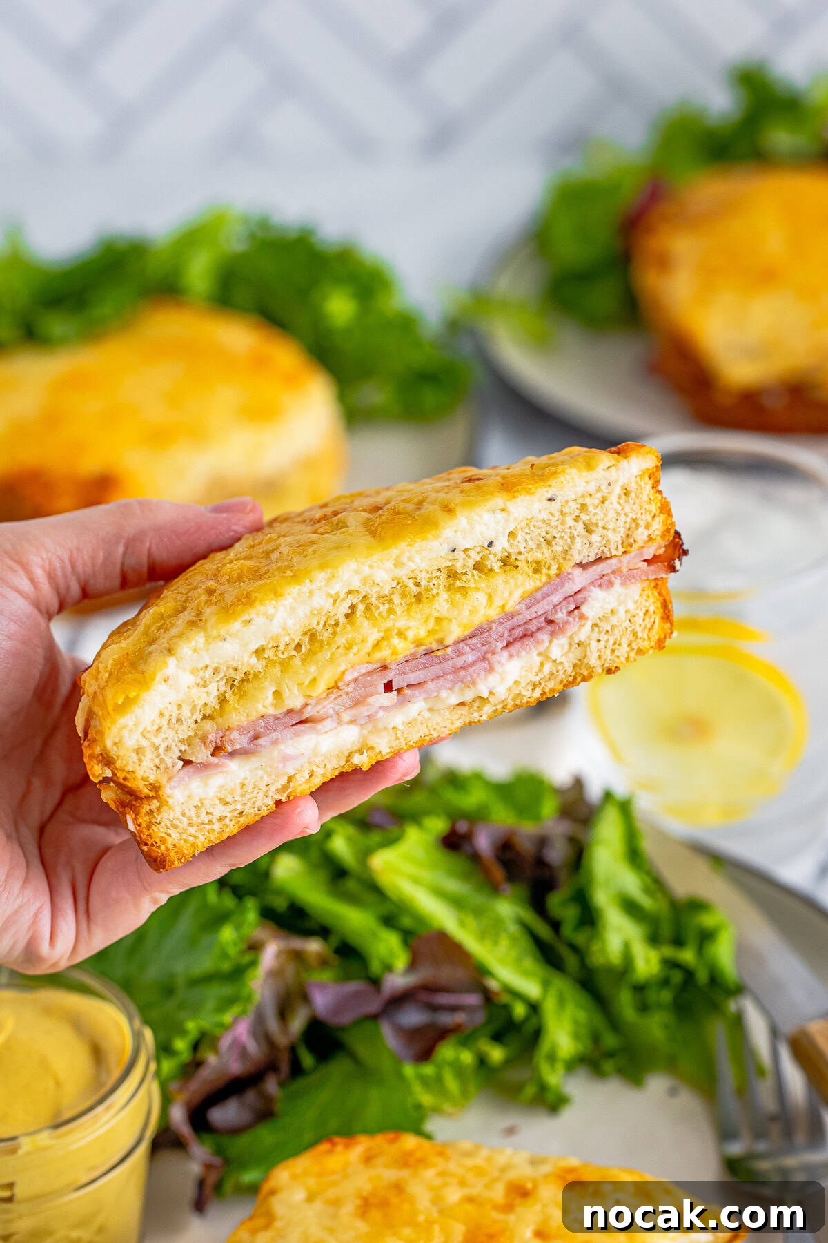 Hand holding up one slice of the sandwich showing the layers.