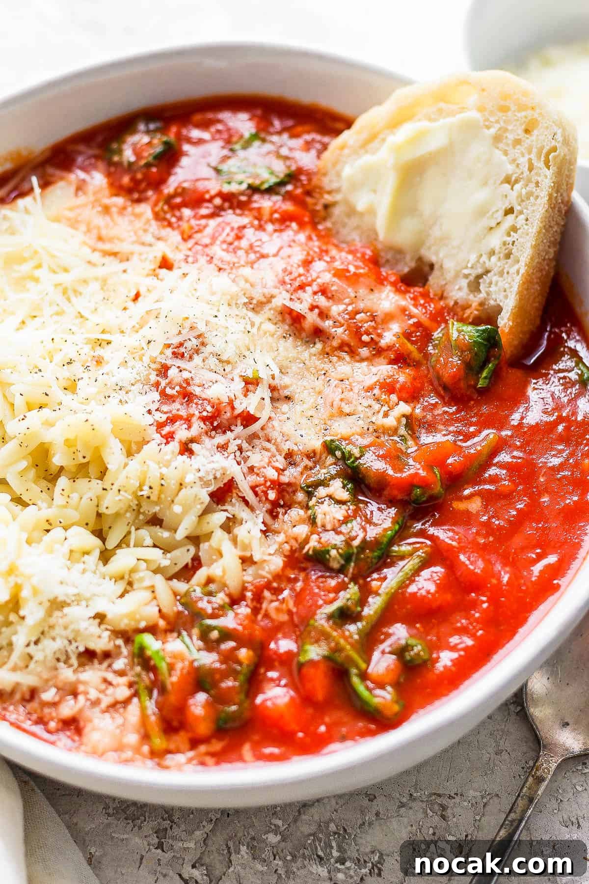 A bowl of tomato florentine soup over some cooked orzo.