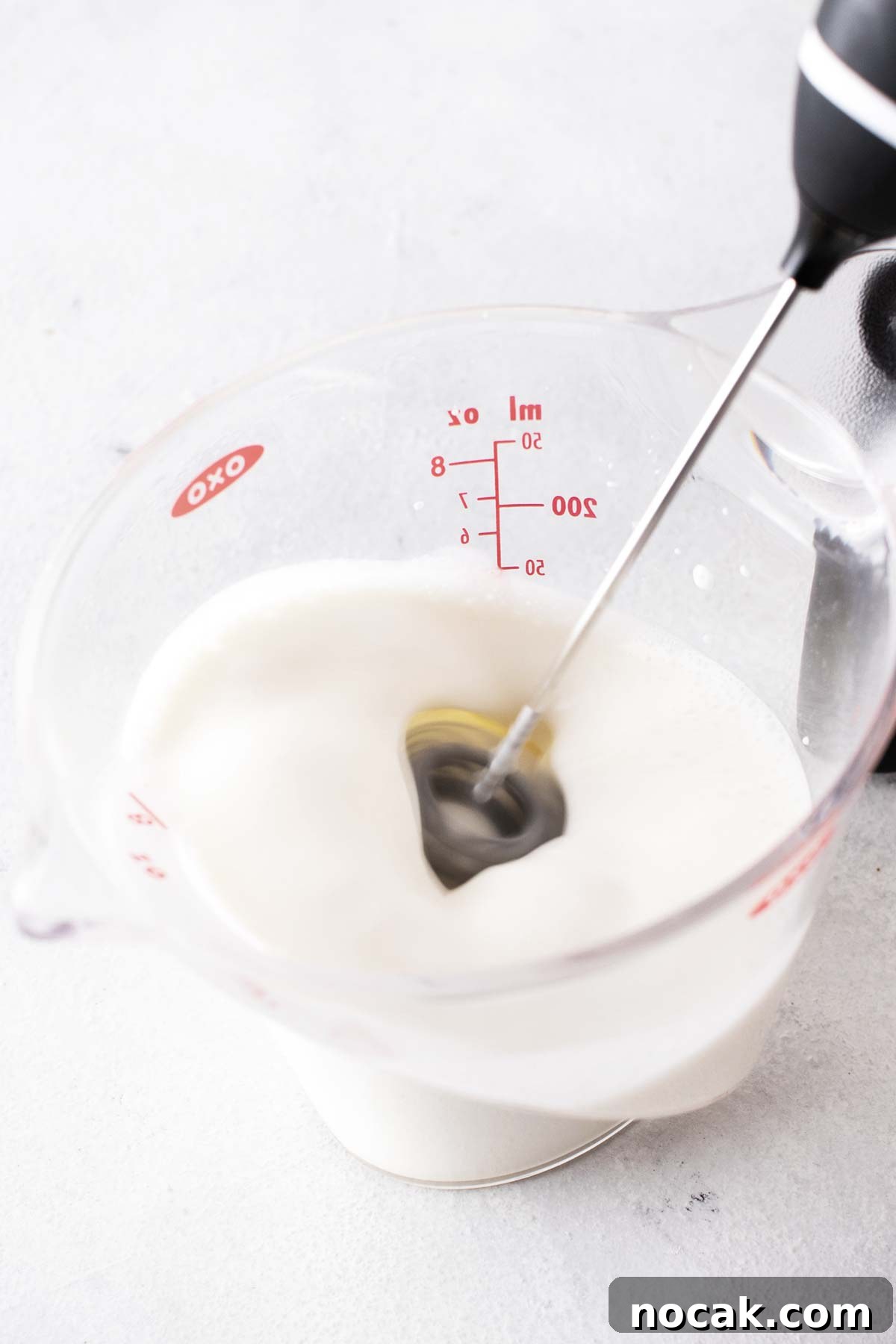 Frothing milk in a measuring cup.