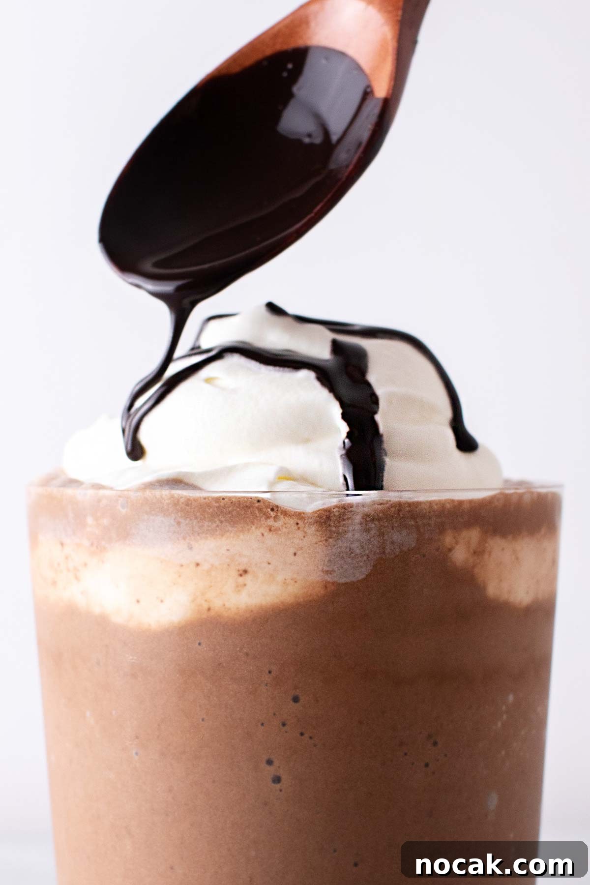 Spooning chocolate syrup on a frappuccino.
