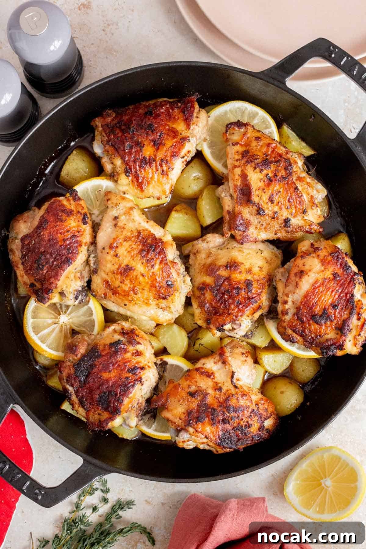 Overhead view of cast iron chicken thighs and potatoes.
