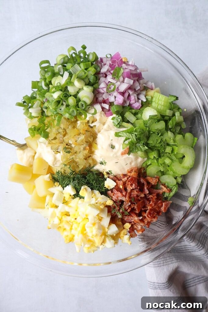 Creamy Potato Salad with Spring Onions and Tangy Dressing 5 glass bowl with potato salad toppings including egg, bacon, celery, red onion, relish, mayo, and spring onions