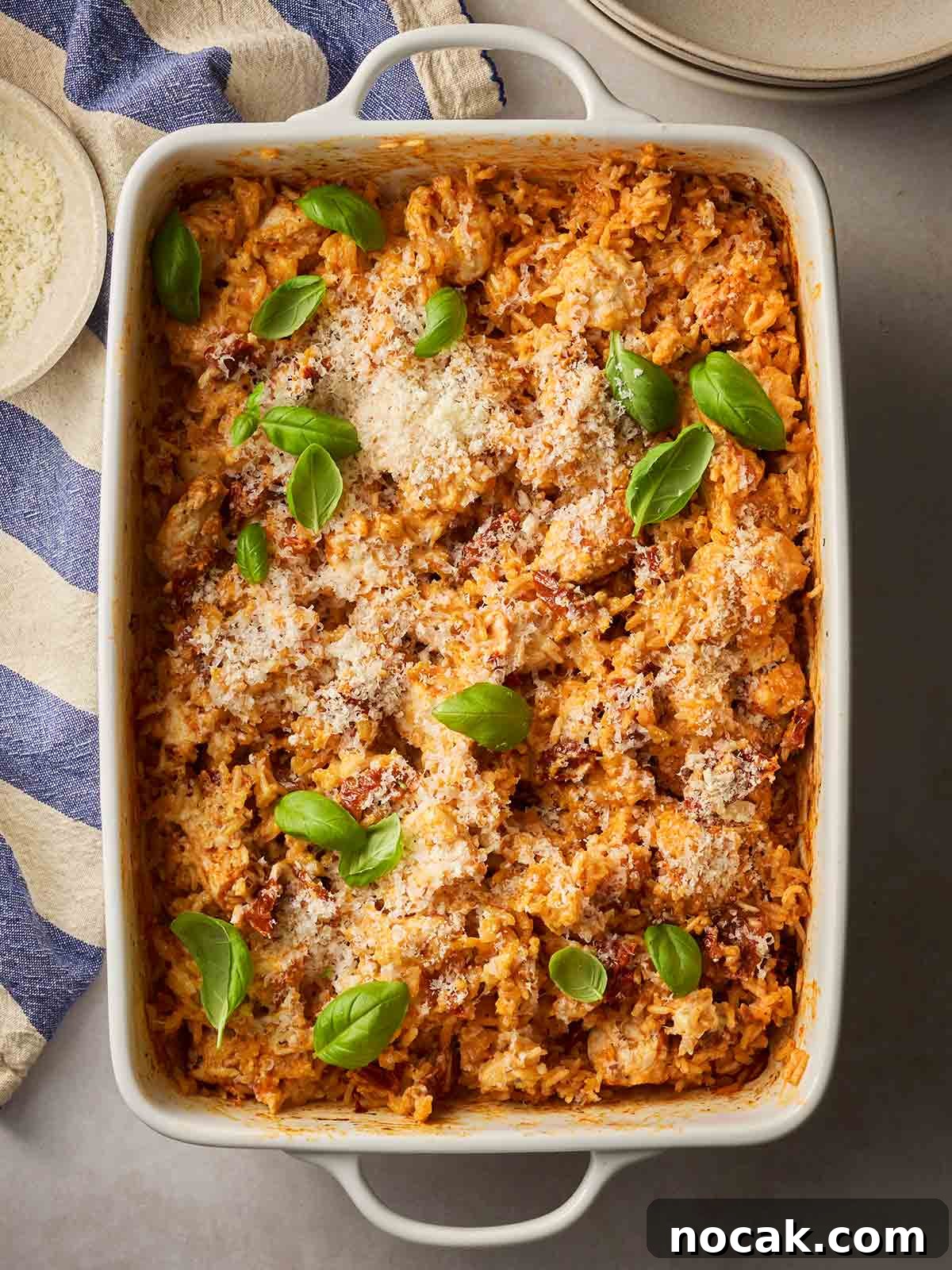 Marry Me Chicken and Rice — One-Pan Dump and Bake Recipe 2 A cooked one pan dish with creamy chicken and rice, with basil over the top, ready to dish up.