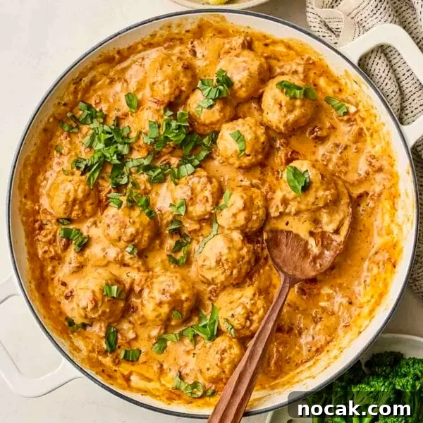 Marry Me Chicken and Rice — One-Pan Dump and Bake Recipe 9 A white pan filled with Marry Me Chicken Meatballs, a creamy sauce and parsley over the top.