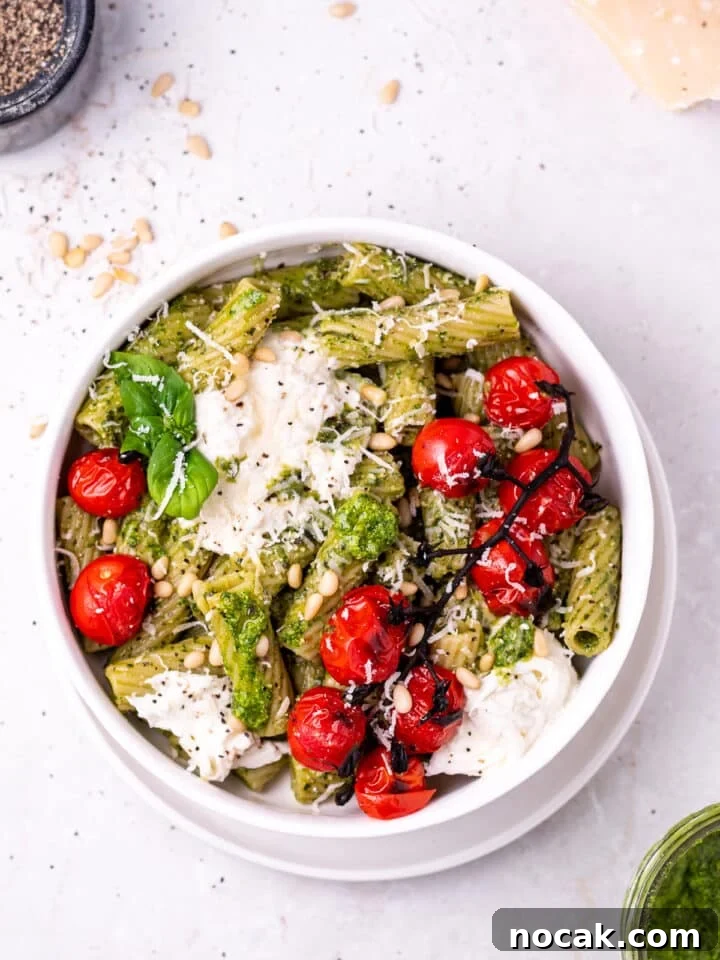 Pesto Rigatoni with Burst Cherry Tomatoes and Creamy Burrata 2 white bowl with rigatoni pasta covered in pesto topped with burrata cheese and burst tomatoes