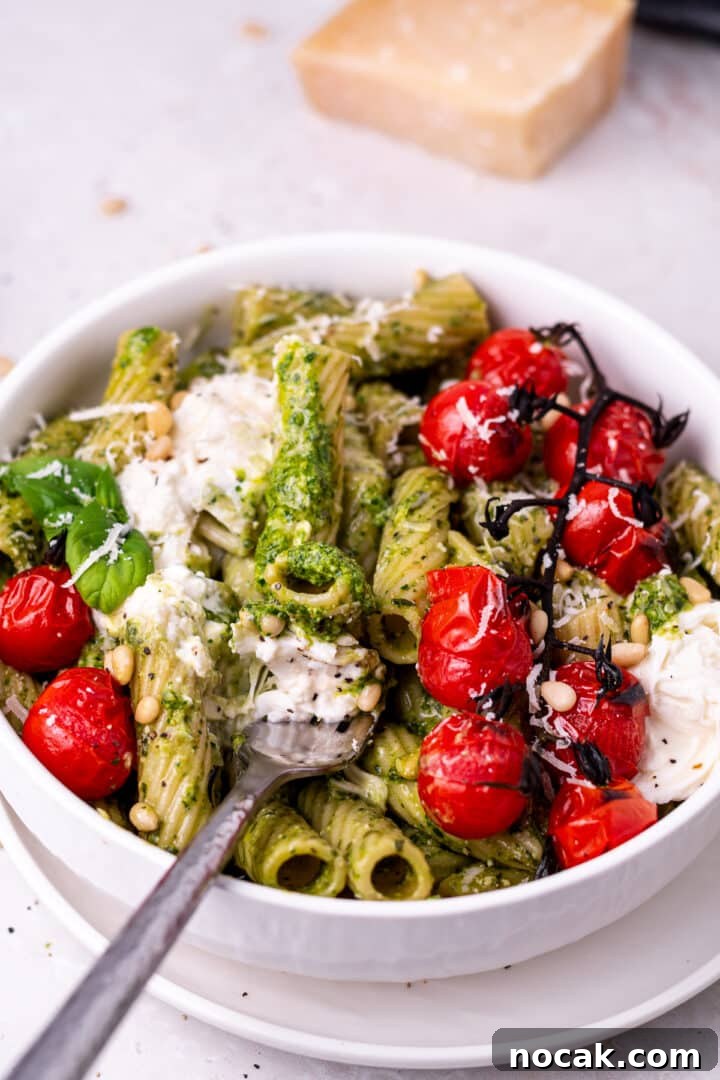 Pesto Rigatoni with Burst Cherry Tomatoes and Creamy Burrata 12 fork with a bite of pesto pasta on it