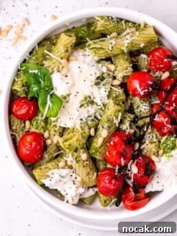 white bowl with pesto pasta, burst tomatoes and burrata cheese