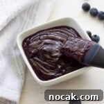 Blueberry BBQ Sauce in a small bowl with a pastry brush inside.