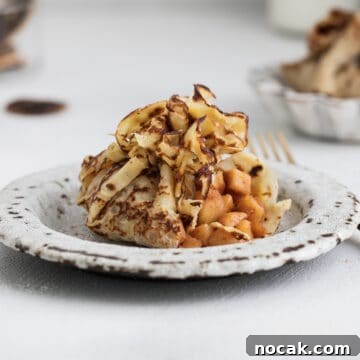 French crepe filled with caramelized apples and cinnamon, served on a dessert table.