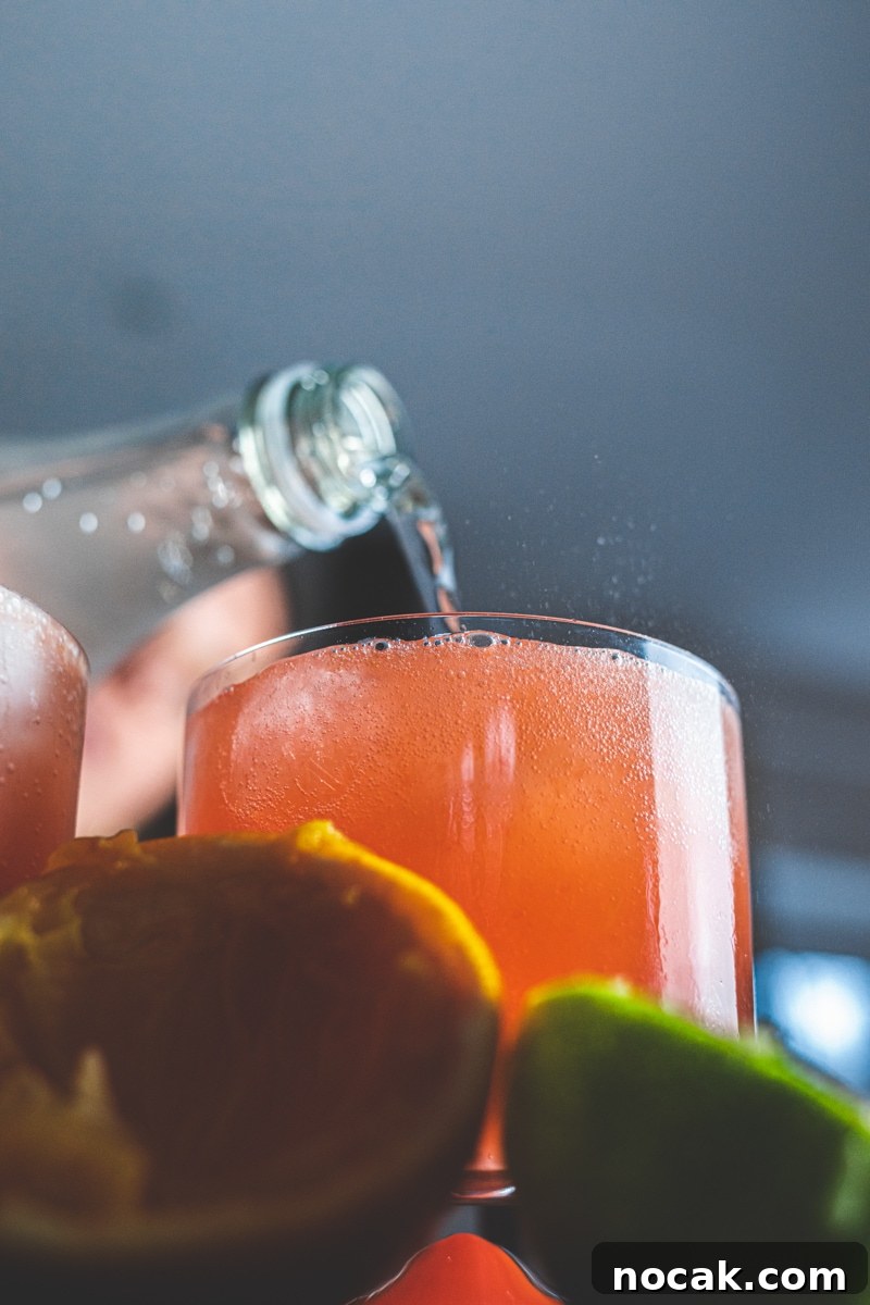 Sparkling Blood Orange Mocktail Recipes for Summer Entertaining 3 Pouring soda water into blood orange mocktail