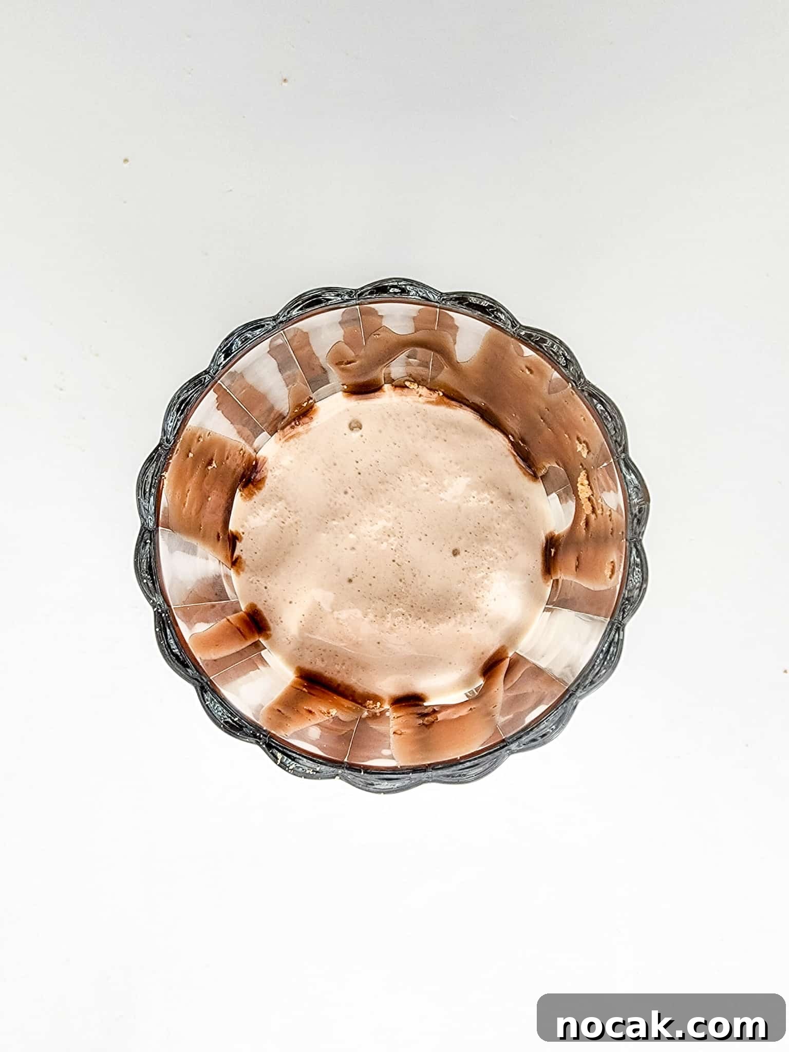 DIY S'mores Frappuccino: Starbucks Copycat Recipe for Home 7 Glass cup filled halfway with frappuccino mixture over top of a white background.
