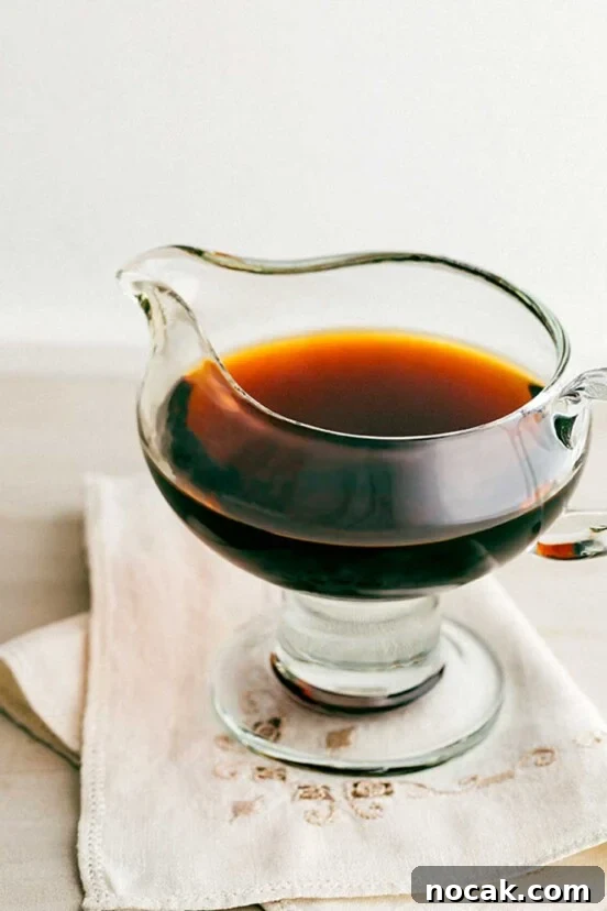 A glass pitcher filled with bourbon syrup on a linen napkin.