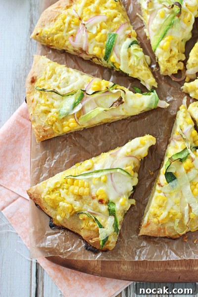 Cheesy & delicious fresh corn and zucchini pizza! With a sauce made of fresh corn kernels and topped with cheese, more corn and zucchini! Several slices of Corn Pizza on a pizza peel.