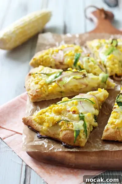 Cheesy & delicious fresh corn and zucchini pizza! With a sauce made of fresh corn kernels and topped with cheese, more corn and zucchini! Side angle view of a sliced Corn Pizza on a pizza peel.