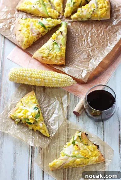 Cheesy & delicious fresh corn and zucchini pizza! With a sauce made of fresh corn kernels and topped with cheese, more corn and zucchini! Several slices of Corn Pizza on a white surface and more on a pizza peel.