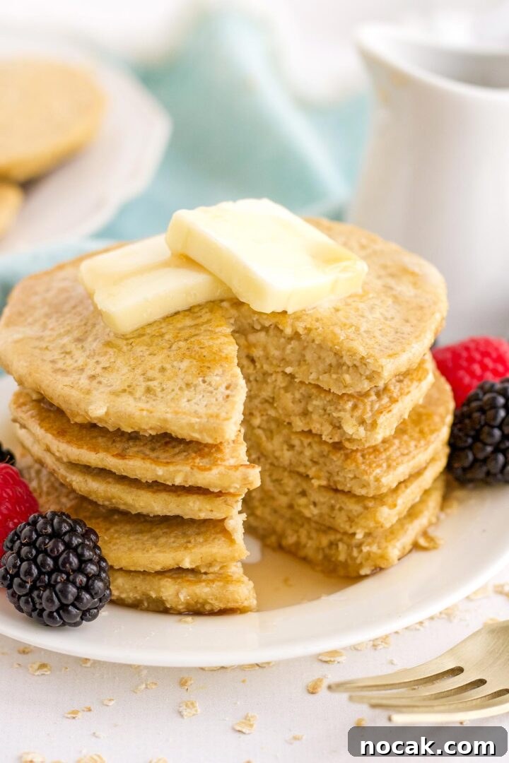 Fluffy Oat Flour Pancakes Recipe for Light, Tender Stacks 2 Stack of oat flour pancakes on a plate with a bite missing.