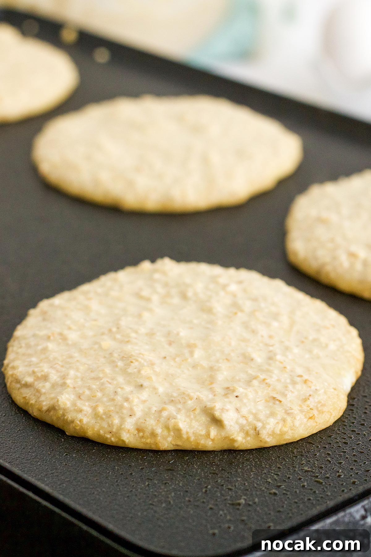 Fluffy Oat Flour Pancakes Recipe for Light, Tender Stacks 6 Cooking oat flour pancakes on a griddle.