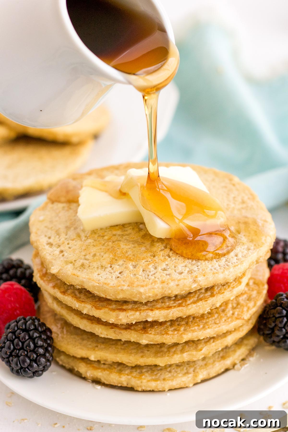 Fluffy Oat Flour Pancakes Recipe for Light, Tender Stacks 8 Pouring syrup over the top of oat flour pancakes on a plate.