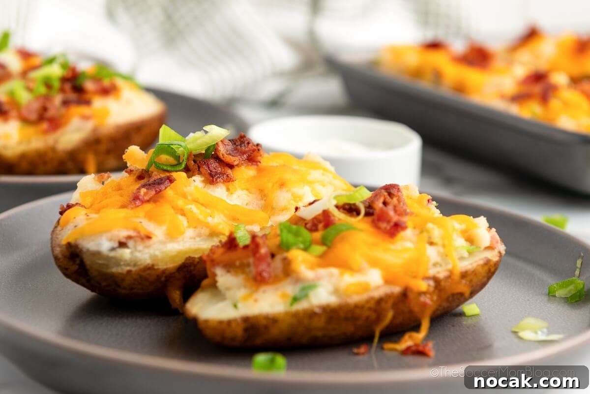 Ultimate Twice-Baked Potatoes Recipe for Crispy, Creamy Filling 3 Twice Baked Potatoes on a platter, with baking pan in background.