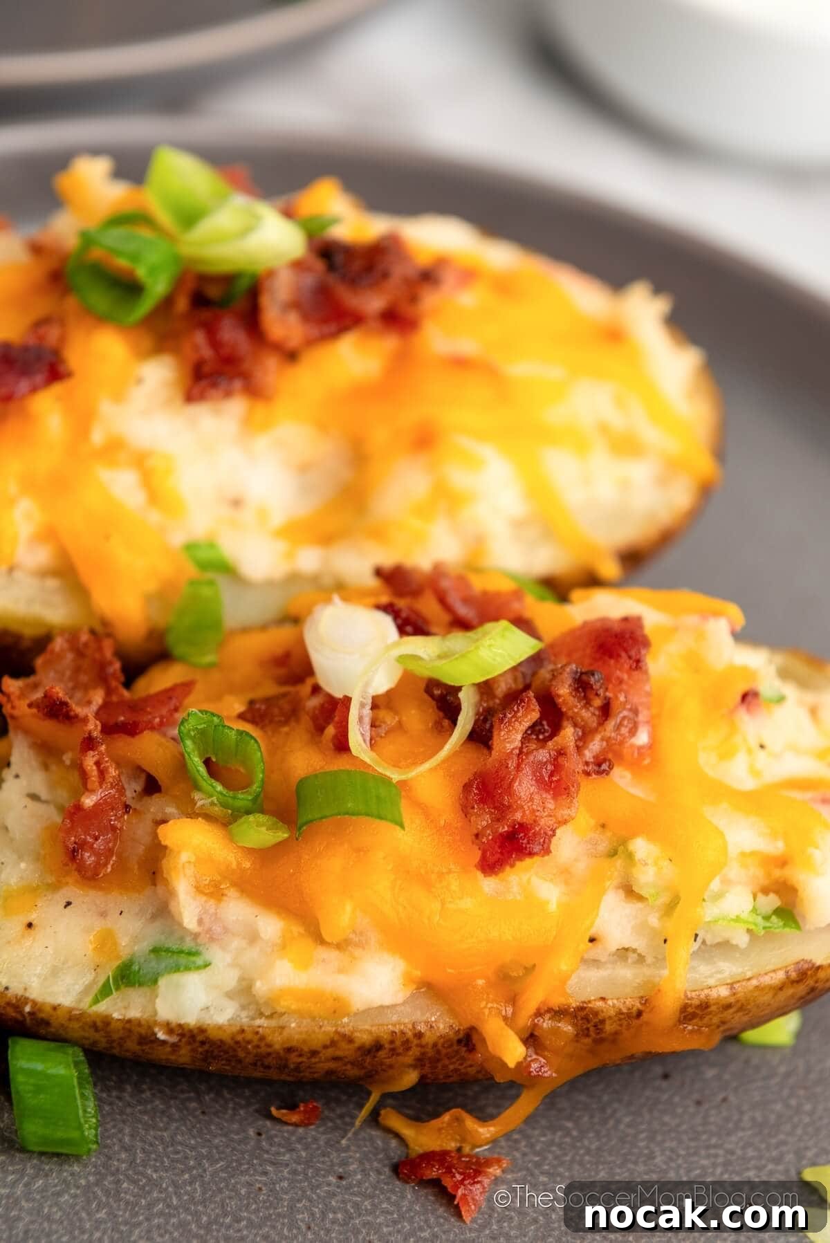Ultimate Twice-Baked Potatoes Recipe for Crispy, Creamy Filling 8 close up of stuffed baked potato shells with cheese.