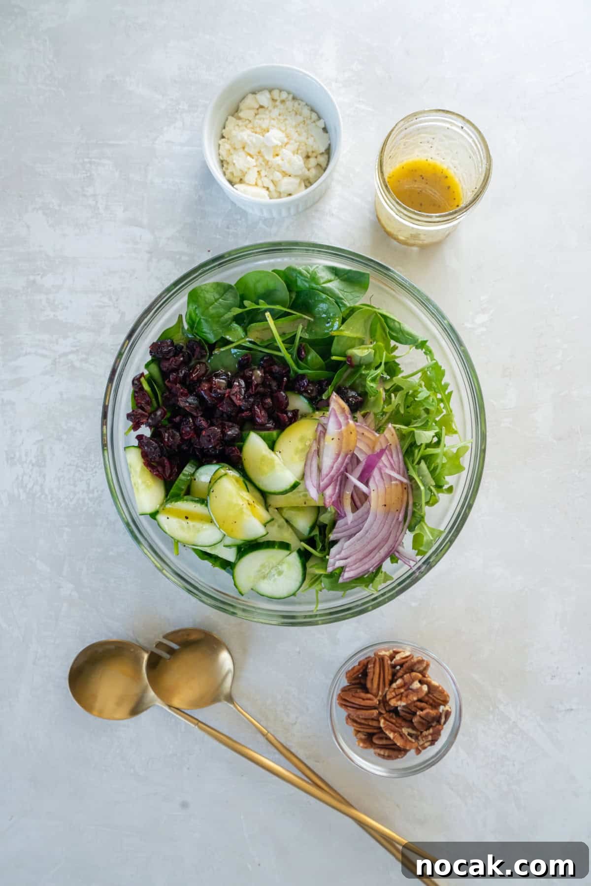 All of the ingredients for spinach and arugula salad in a bowl before mixing in the salad dressing.