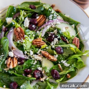 Spinach and arugula salad is in a white bowl ready for serving.
