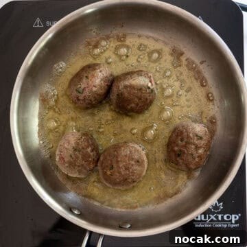 Classic Italian Fried Meatballs Recipe — Crispy, Savory Plates 7 Meatballs browned while frying in a saucepan.